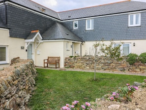 A cottage with a stone wall, a wooden bench, and a small garden with pink flowers. - Sorrel Cottage (Padstow)