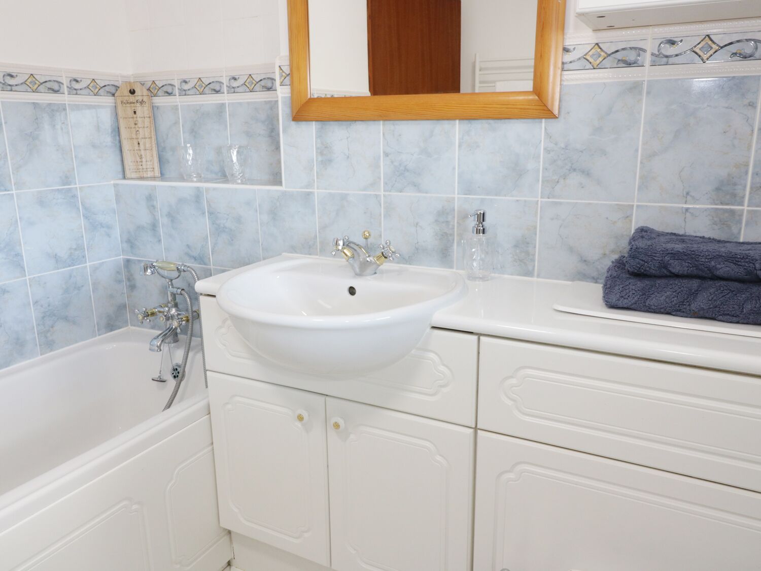 Un baño con un lavamanos blanco, un espejo y una bañera.