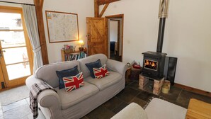Ein gemütliches Wohnzimmer mit einer Couch, einem Kamin und einer Holzbalkendecke.