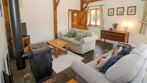 Ein gemütliches Wohnzimmer mit Kamin, einer Couch, einem Couchtisch und einem Holzkasten.