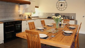 A modern kitchen with a wooden dining table set for four, equipped with chairs, plates, glasses, and cutlery.