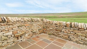 A stone wall with a tiled floor, surrounded by a grassy landscape.