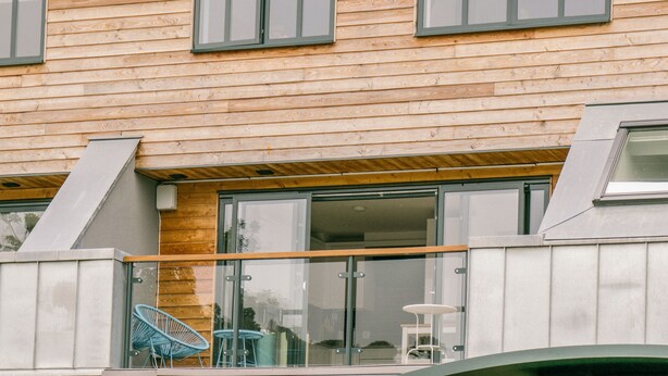 A modern wooden building with large windows and a balcony with chairs. - Sidings at Brunel Two (Lostwithiel)