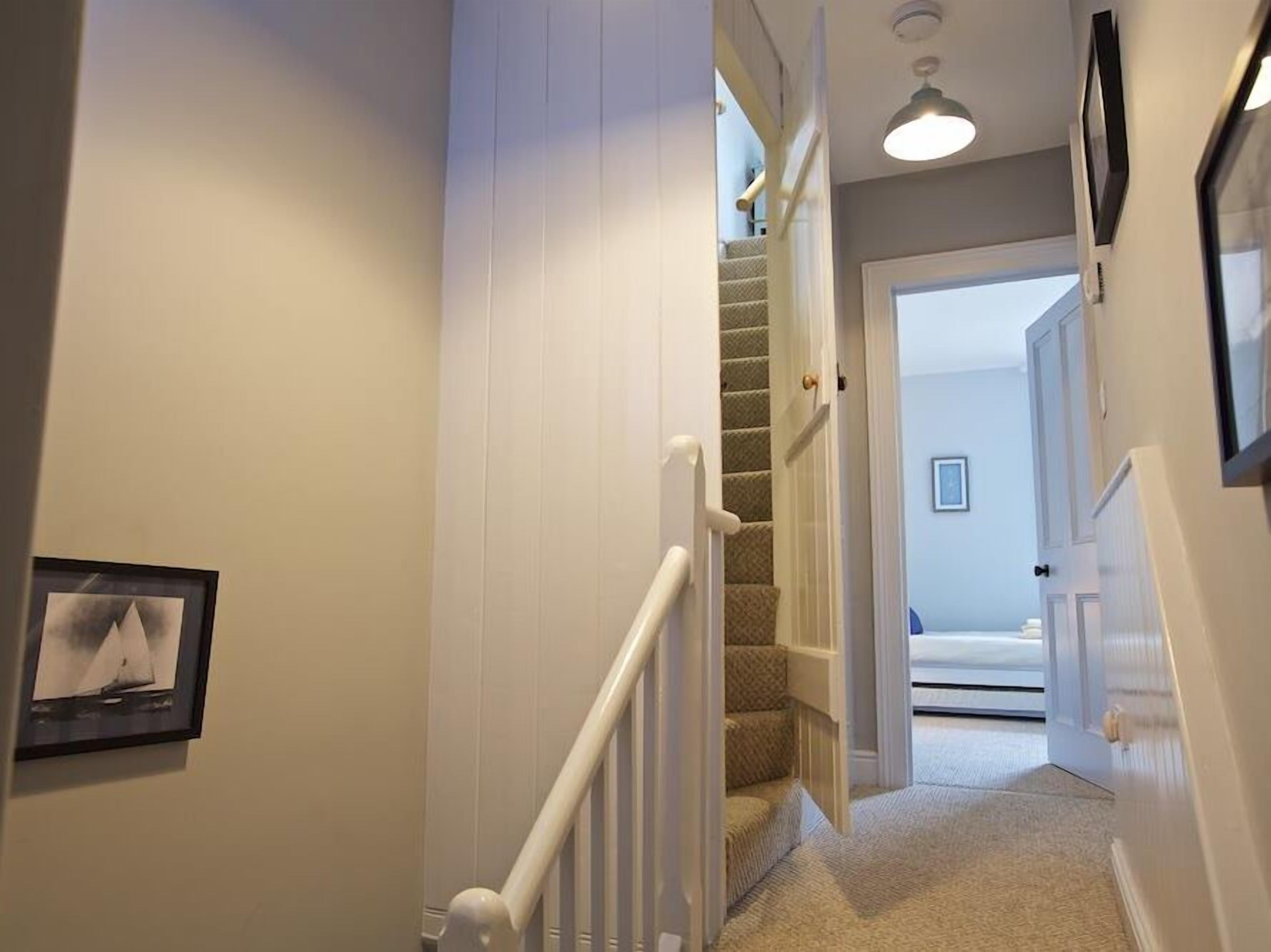 A hallway with a carpeted staircase leading to another room.