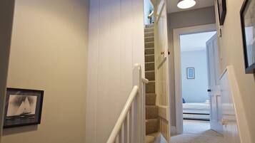 A hallway with a carpeted staircase leading to another room.