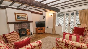 A cozy living room with a fireplace, a television, and comfortable seating. - Laburnum Cottage (Hope Valley)