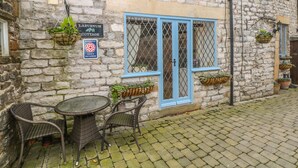 A stone building with a sign for 'Laburnum Cottage' indicating self-catering. There is a table and chairs outside. - Laburnum Cottage (Hope Valley)