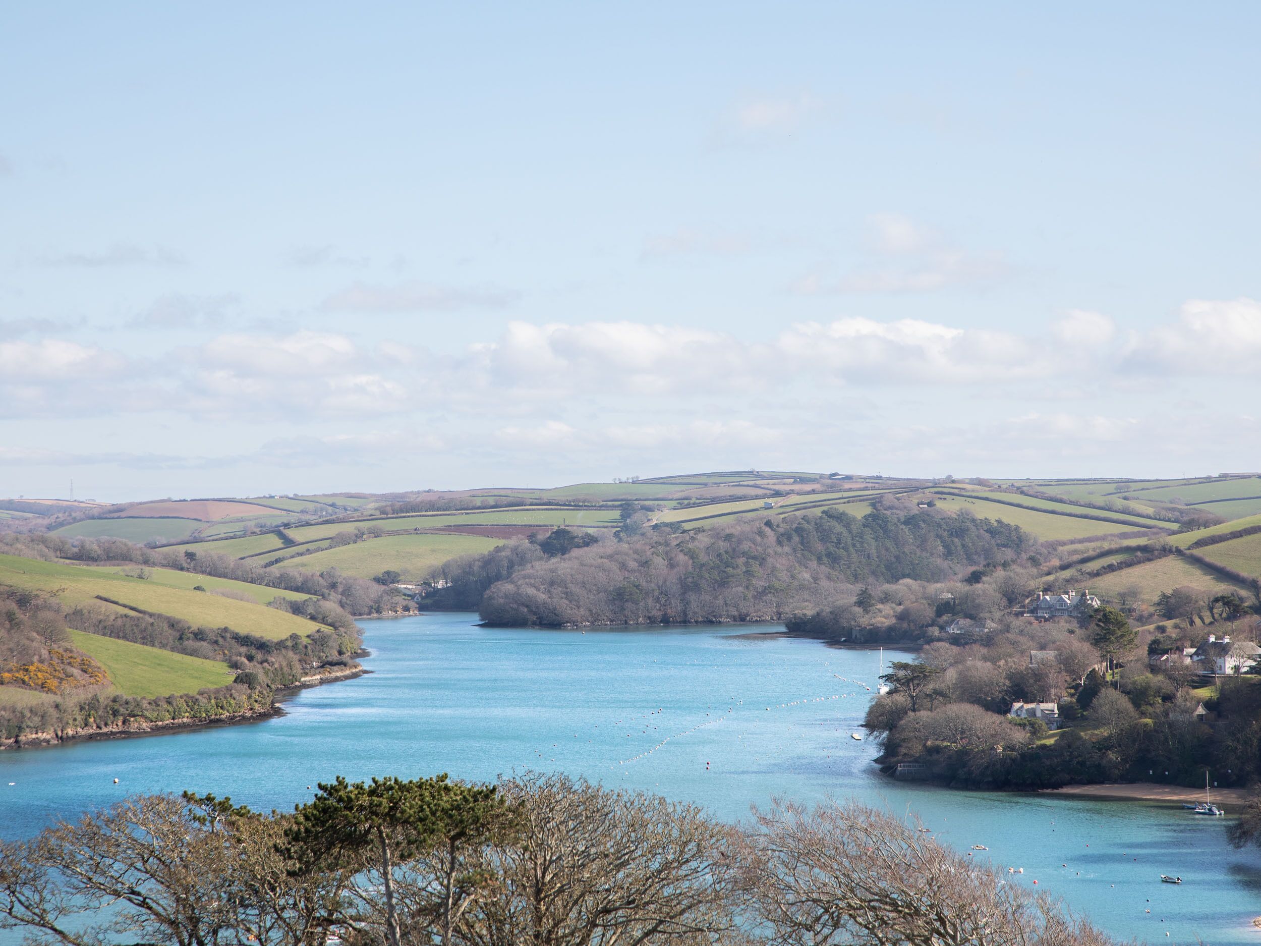 A river valley with houses on the banks and a clear sky.