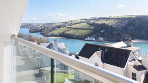 A coastal view from a balcony overlooking a bay with houses and hills in the distance. - 4 Blue View (Salcombe)