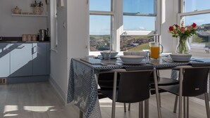 A modern kitchen with a dining area, large windows, and a view of the countryside. - 4 Blue View (Salcombe)