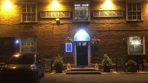 A brick building with illuminated signs reading "LION" and "INN". - The Theberton Lion (Leiston)