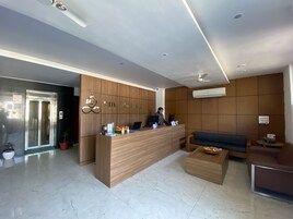 Una recepción con detalles de madera, una zona de estar con sofá y un suelo de baldosas.