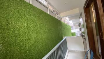 A hallway with a green artificial grass wall, a metal railing, and a blue chair.