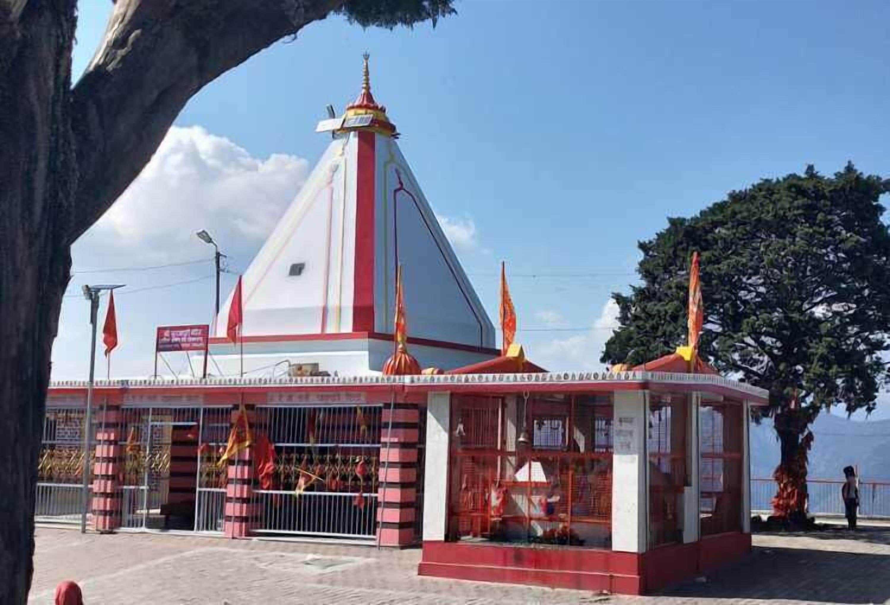 Ein kleiner Tempel mit einer rot-weißen Struktur, einem spitz zulaufenden Dach und einer Flagge auf der Spitze.