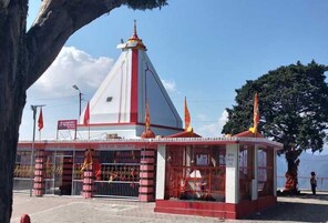 A small temple with a red and white structure, a pointed roof, and a flag on top.