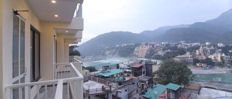 A high-rise building with balconies overlooking a coastal town and mountains.
