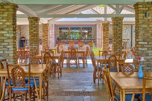 Enjoy dining in a casual, open space with tables and brick pillars, surrounded by a variety of beverages.