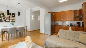 A modern kitchen with wooden cabinets, a refrigerator, and a dining area with a table and chairs.