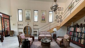 Un salón amplio con techo alto, una escalera y una estantería llena de libros.