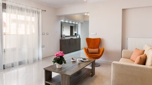 A modern living room with a wooden coffee table, a sofa, an orange armchair, and a potted plant. - Bright Modern Flat next to Beach (Platanias)