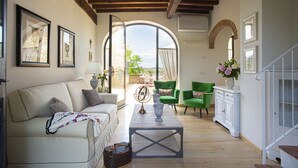 A spacious living room with a sofa, armchairs, a coffee table, and a view through a large arched window. - Private house in the Chianti area for 12 persons, pool and A / C (Tavarnelle Val di Pesa)