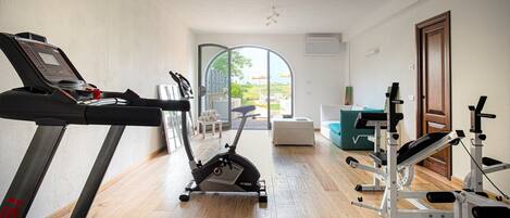 Un gimnasio en casa con cinta de correr, elíptica y banco para pesas.