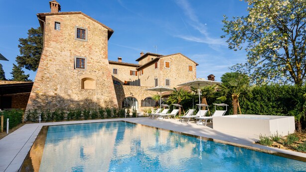 A swimming pool with lounge chairs and umbrellas, a stone building with arched windows, and lush greenery. - Private house in the Chianti area for 12 persons, pool and A / C (Tavarnelle Val di Pesa)