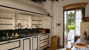 A kitchen with white cabinets, black countertops, and a wooden floor. There is a window with a view of greenery outside. - Private house in the Chianti area for 12 persons, pool and A / C (Tavarnelle Val di Pesa)