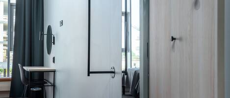 A modern hotel room with a desk, chair, and a large mirror.
