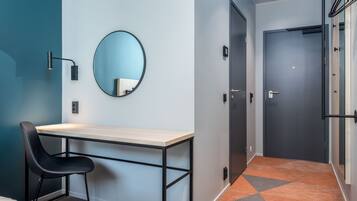 A modern hotel room with a desk, chair, and a large mirror.