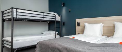 A room with a bunk bed, a single bed, and a wooden headboard.