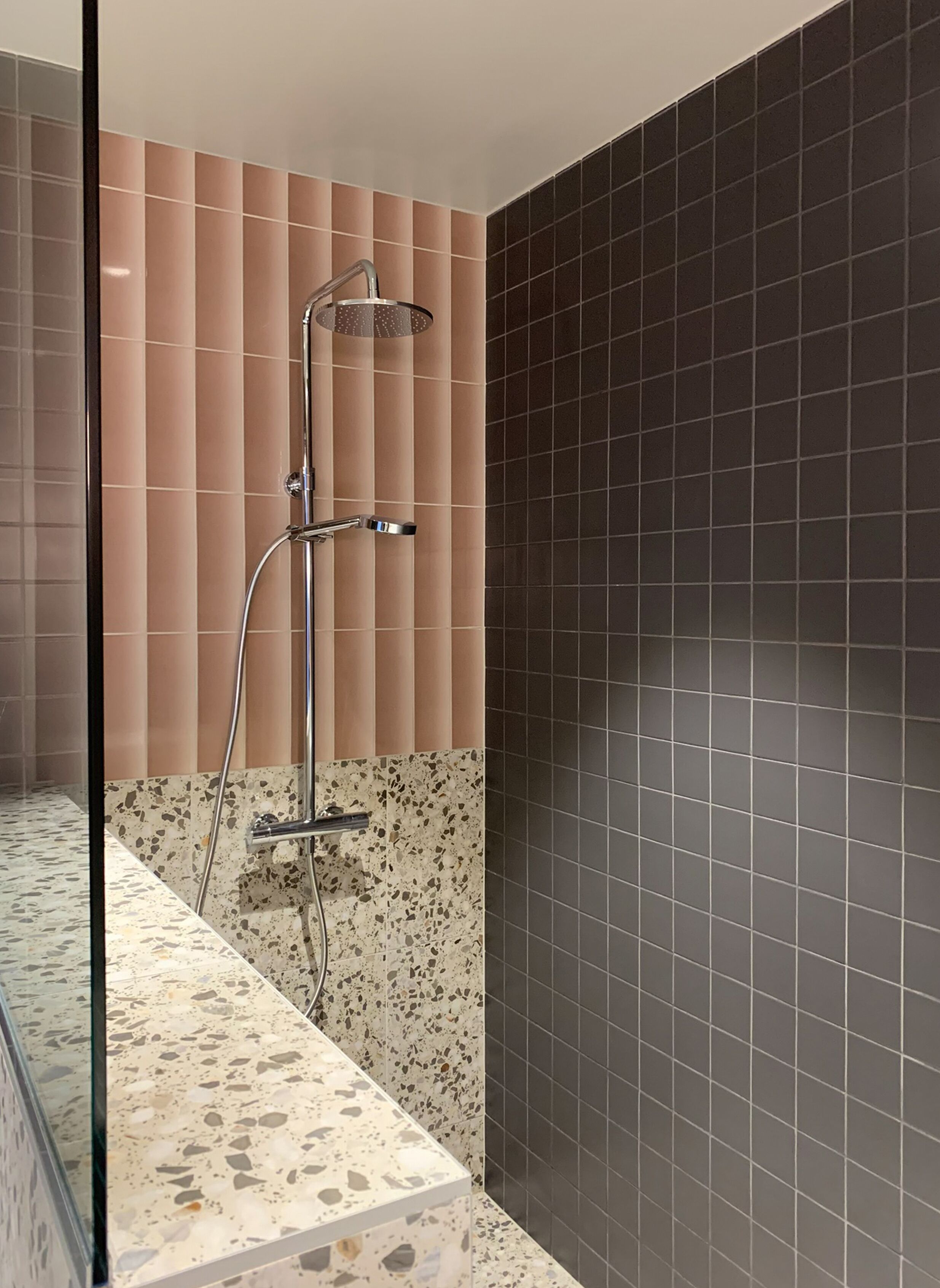 A modern bathroom with a shower, a tiled floor, and a wall with a mix of tile patterns.