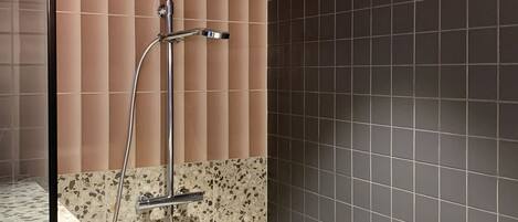 A modern bathroom with a shower, a tiled floor, and a wall with a mix of tile patterns.