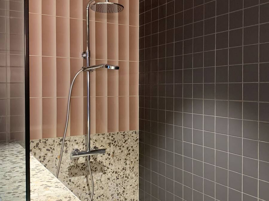 A modern bathroom with a shower, a tiled floor, and a wall with a mix of tile patterns.