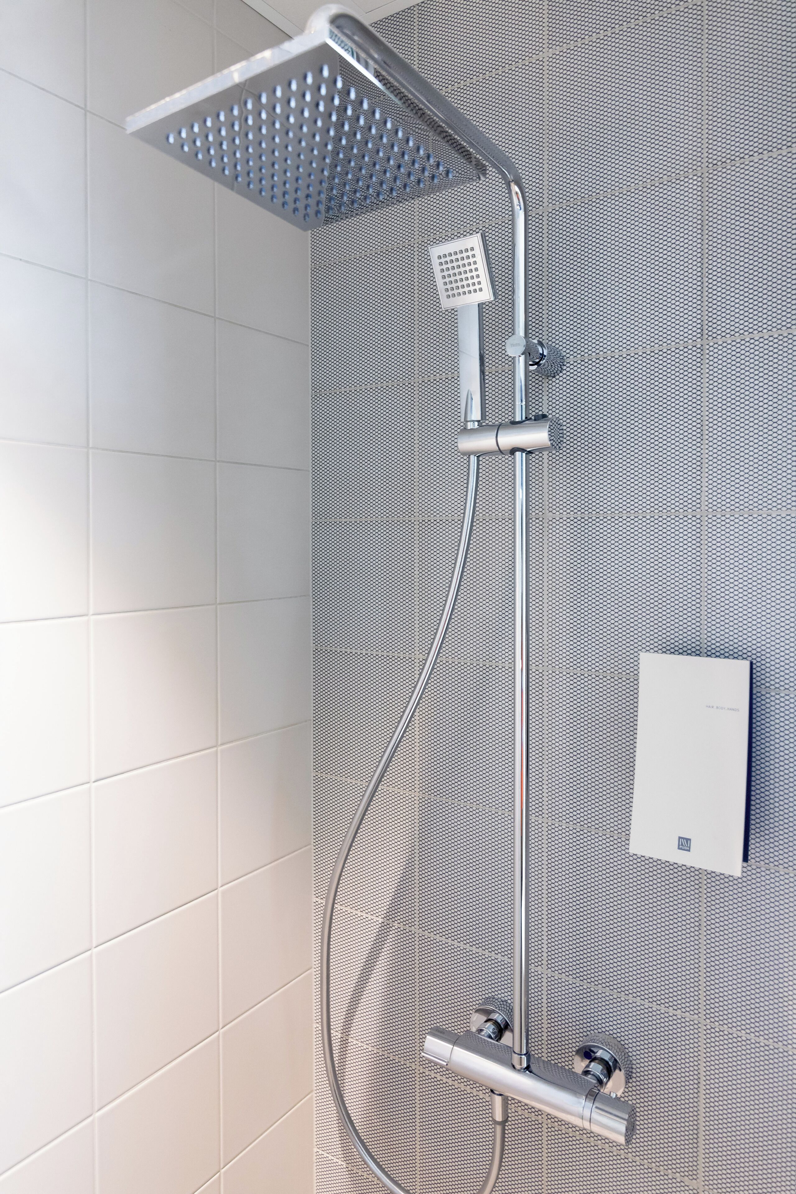 Eine moderne Dusche mit einer quadratischen Duschbrause und einem Handbrausehalter.