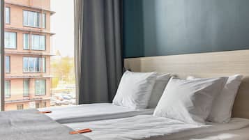 A hotel room with two beds, a view of a building outside, and a curtain.