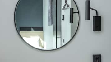 A round mirror on a wall, a black desk, and a black chair.