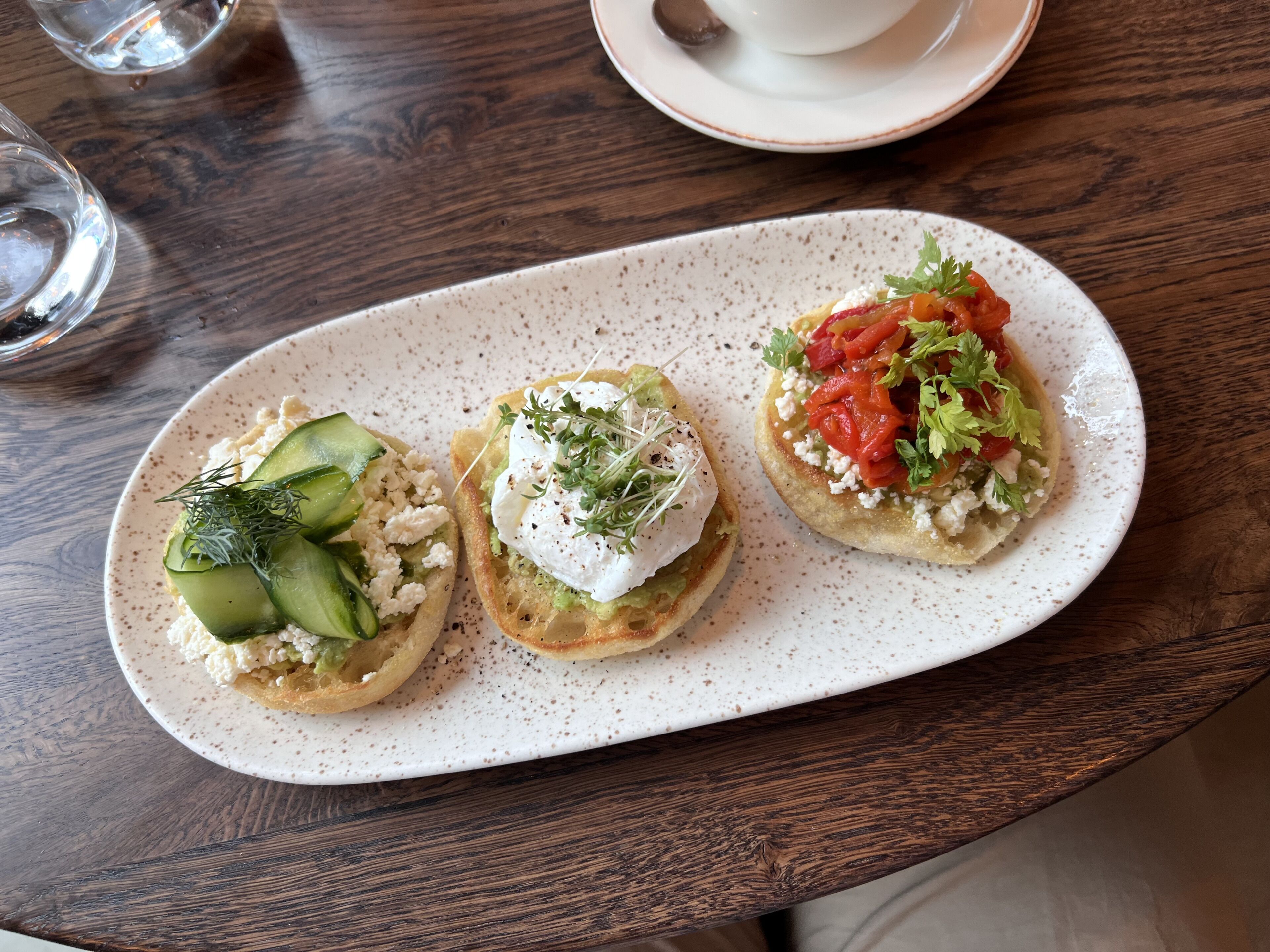 A plate with three open-faced sandwiches on a speckled ceramic plate.