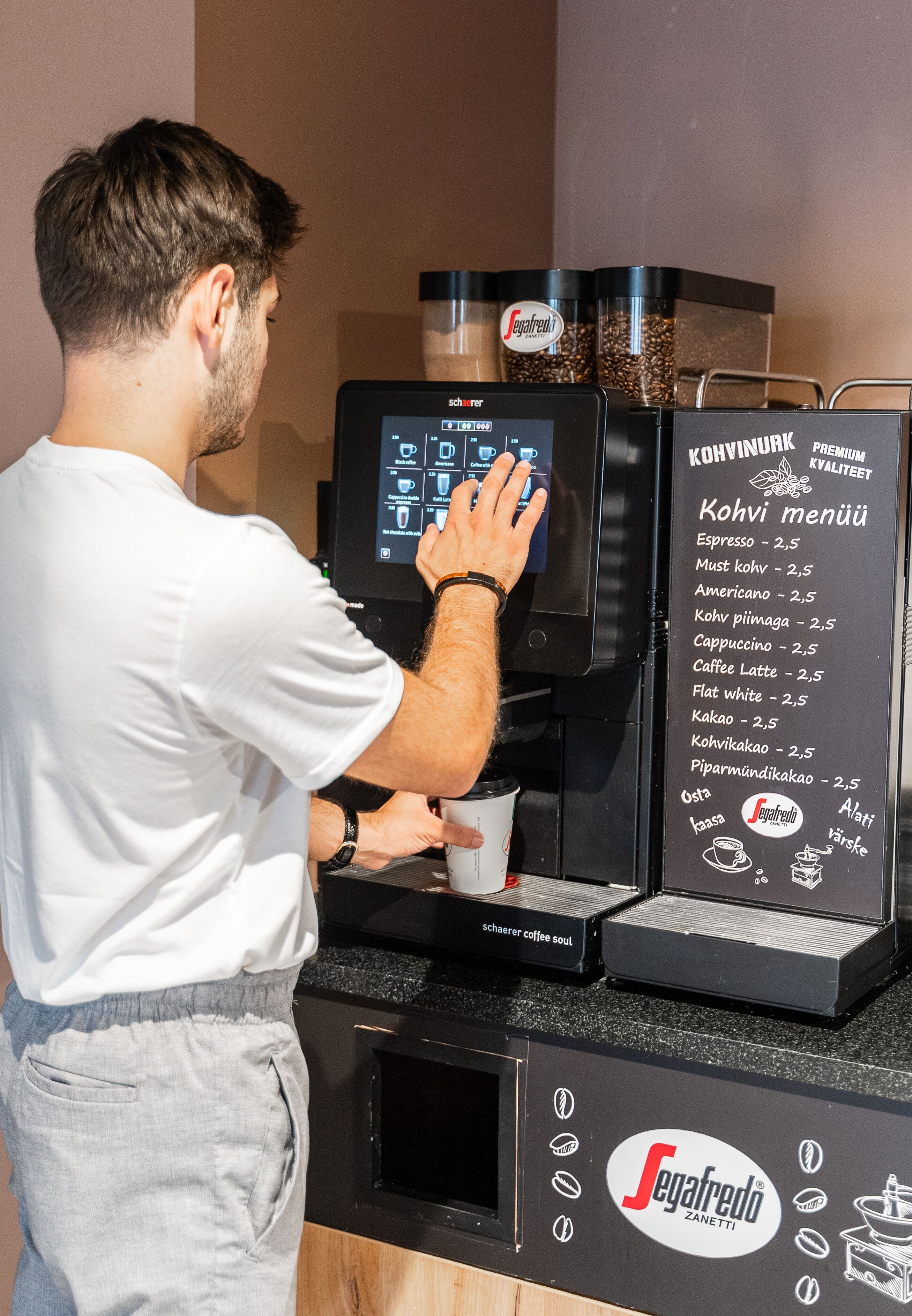 A person operating a coffee machine with a menu display.