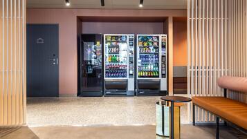 Een moderne lobby met een receptiebalie, een zithoek en automaten.