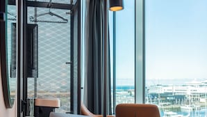 A modern office space with a laptop on a wooden desk, a chair, and a view of a marina through large windows. - Citybox Tallinn City Center  (Tallinn)