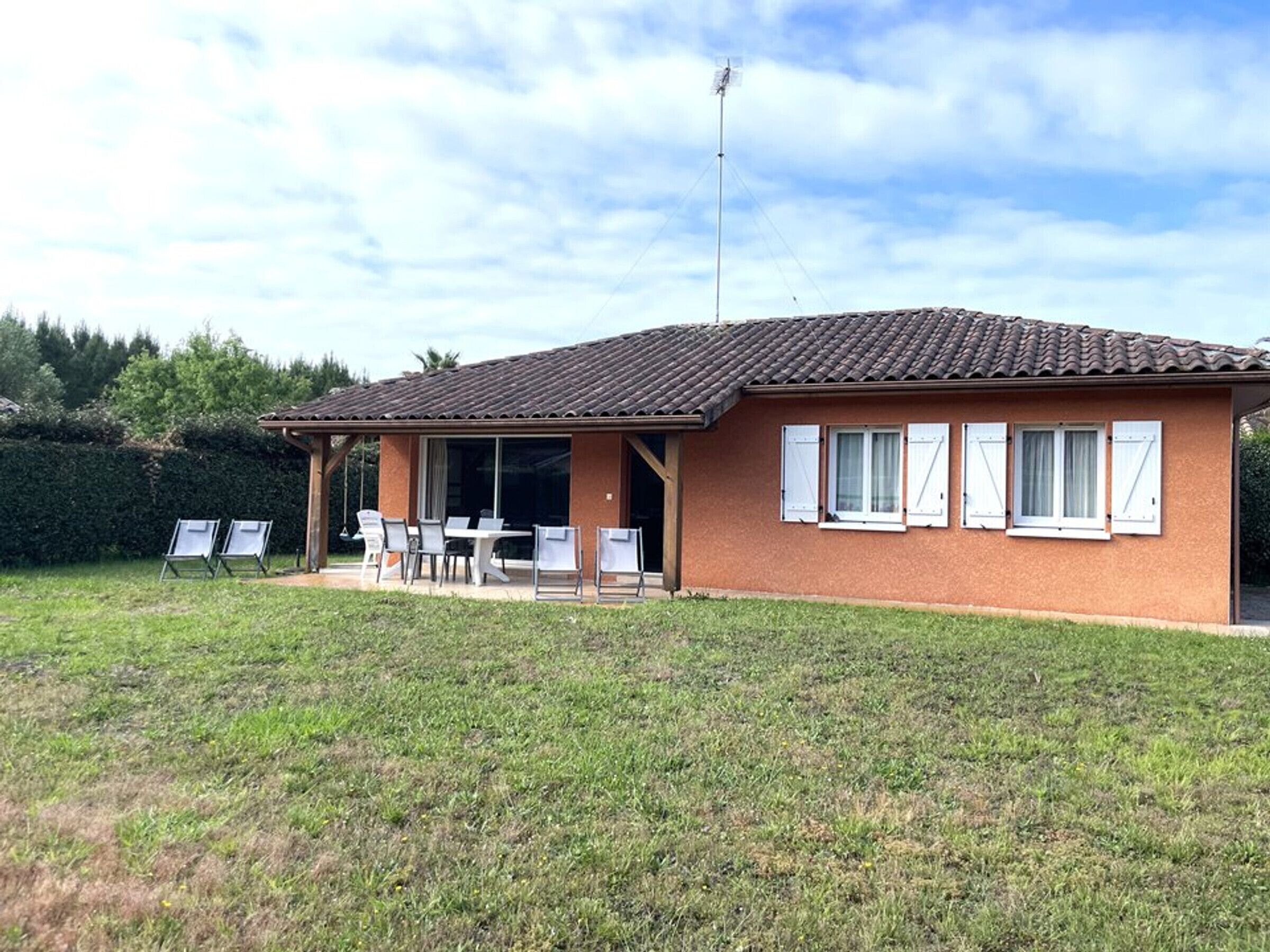 Une maison de plain-pied avec un toit en tuiles, un patio couvert avec des meubles d’extérieur et un mât pour drapeau.