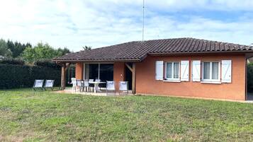 Une maison de plain-pied avec un toit en tuiles, un patio couvert avec des meubles d’extérieur et un mât pour drapeau.