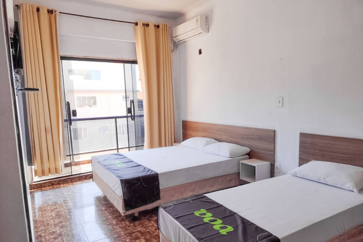 Ein Hotelzimmer mit zwei Betten, einer Schiebetür und Blick auf die Stadt.