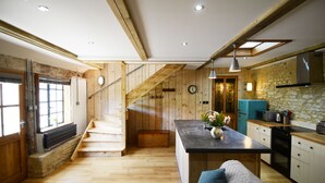 Une cuisine moderne agrémentée d’éléments en bois, dotée d’un îlot central et d’un escalier menant à un niveau supérieur.