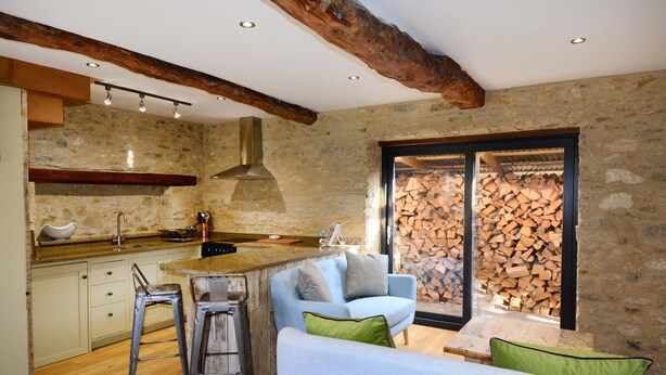 Une cuisine rustique avec des murs en pierre, des poutres en bois et un poêle encastré.