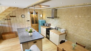 Une cuisine chaleureuse avec un plancher en bois, un îlot central et un coin repas comprenant une table et des chaises en bois.