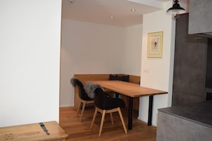 A modern kitchen with a wooden table and chairs, a grey cabinet, and a framed picture on the wall. - Apartment Jungfrauview (Lauterbrunnen)