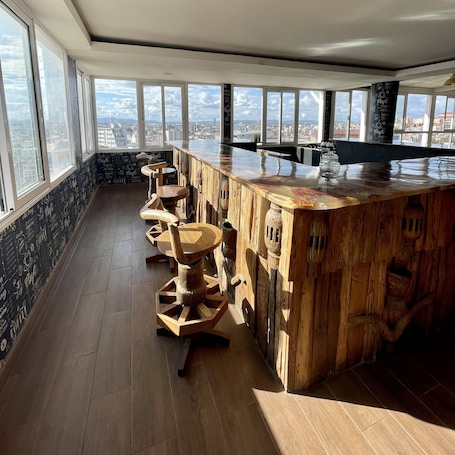 A high-rise bar with a wooden interior, large windows, and a city view.