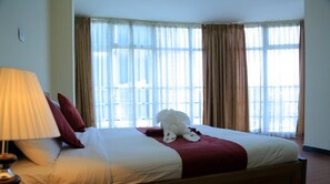 A hotel room with a large bed, a lamp, and curtains. - Bruhway Hotel (Addis Ababa)